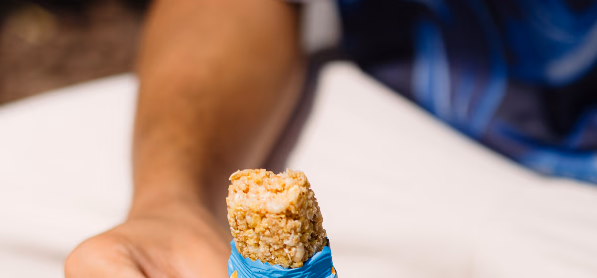 Two hands opening a cereal bar during a break.